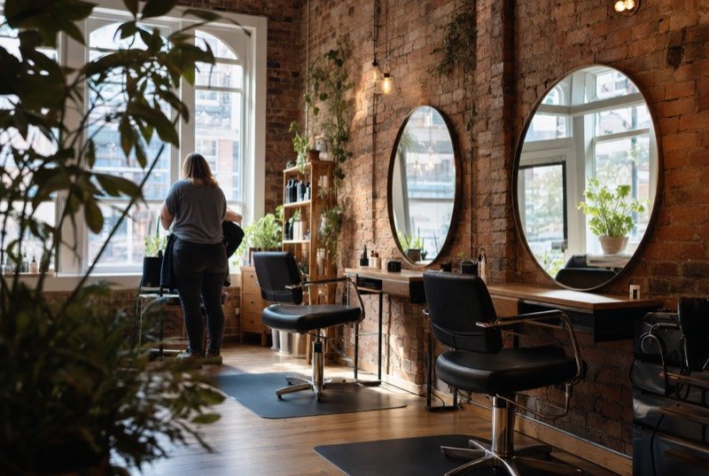 A bright hair salon with red-brick walls and tall windows
