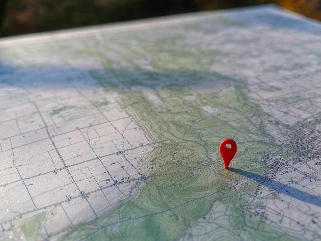 A red pin pushed into a printed topographic map